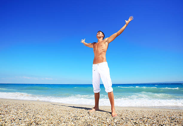 istock Man with open hands stands and enjoys on the beach. 183759142