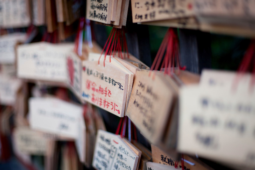 Ema boards, small wooden plaques inscribed with wishes and prayers and Good luck messages, on display at Shinto shrine, close up.