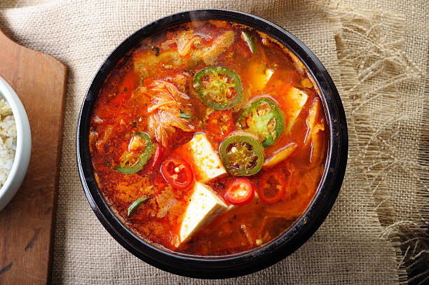A bowl of red Kimchi soup on rough material Kimchi Soup with Tofu, Korean Cuisine. Kimchi stock pictures, royalty-free photos & images
