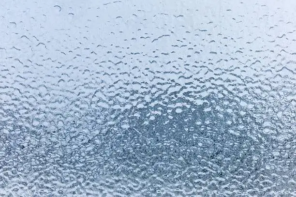 A window on a building is frozen and completely covered in ice after an ice-storm and freezing rain.