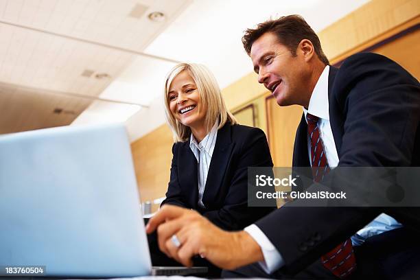 Man Presenting Business Ideas To Woman On Laptop Stock Photo - Download Image Now - 40-49 Years, 50-59 Years, Administrator