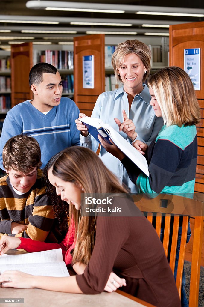 Groupe de jeunes étudiants avec le professeur dans la bibliothèque - Photo de 14-15 ans libre de droits