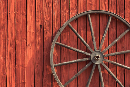 Old wheel on barn wall.