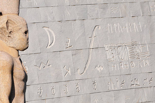 The beautiful exterior of the Alexandria Library in Alexandria, Egypt. The focus is on the ancient statue on the left; the background is the building exterior, engraved with characters and symbols.