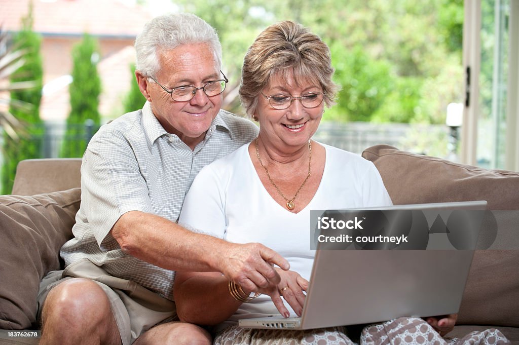 Ancianos pareja trabajando en una computadora portátil - Foto de stock de 50-59 años libre de derechos