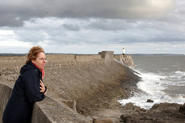 Mature windswept woman at sea wall