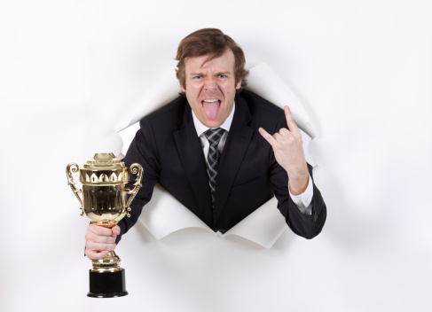 Photo of happy caucasian man holding cup award and showing thumb up.