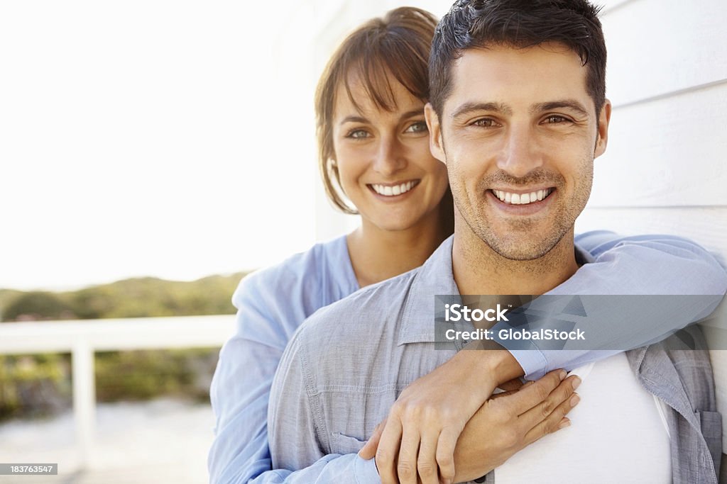 Happy, romantic couple "Portrait of an attractive, young woman embracing her husband from behind" 20-29 Years Stock Photo