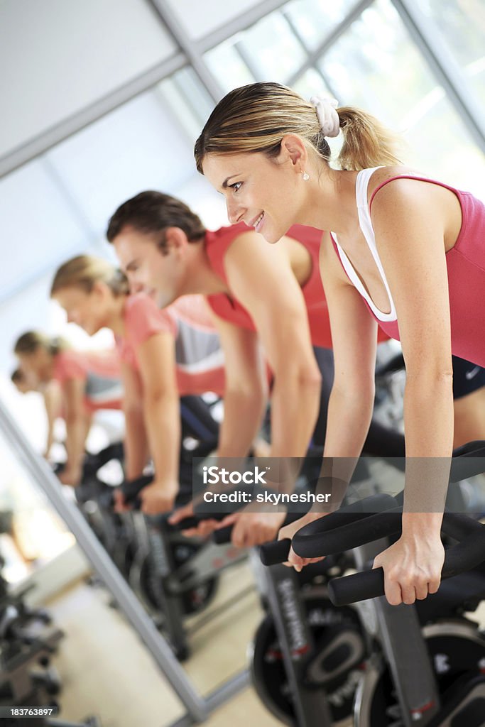 Young people training on exercise bike at the gym A group of young people training on exercise bike at the gym. Exercising Stock Photo