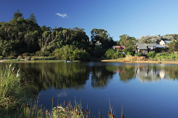 istock River with grass, trees and cabins reflected on the water 183764192