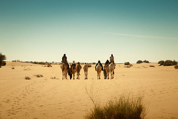 Caravan of travelers in Libyan Sahara desert stock photo
