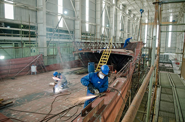 Metalworker Welding new steel plates on a ship's hull during repair work on a ship in a dry dock. dry dock stock pictures, royalty-free photos & images