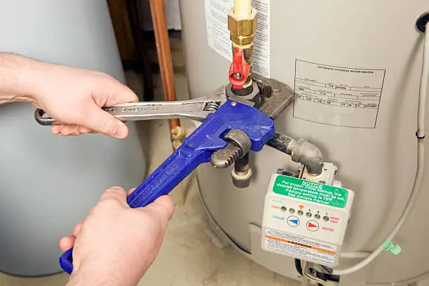 Photo of Plumber Pipe and Adjustable Wrenches on Water Heater Gas Line