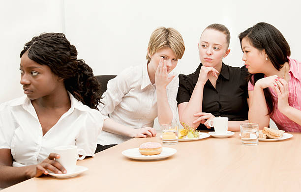 Workplace Exclusion A young woman looks away as her colleagues gossip behind her back.Click segregation stock pictures, royalty-free photos & images