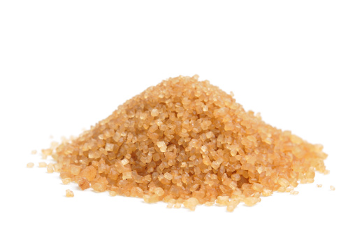 A heap of unrefined raw cane sugar isolated on a white background.