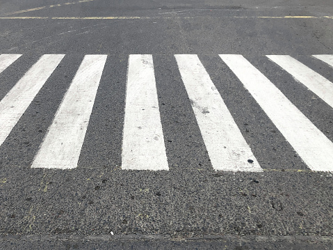 Crosswalk or zebra crossing at intersection. With motorists passing in the background