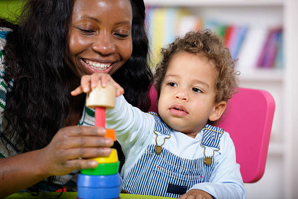 istock Childminder And Toddler Playing With Multi-coloured Rings 183766435