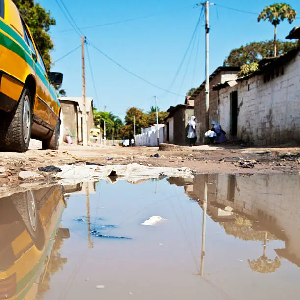 African town street in puddle reflection.