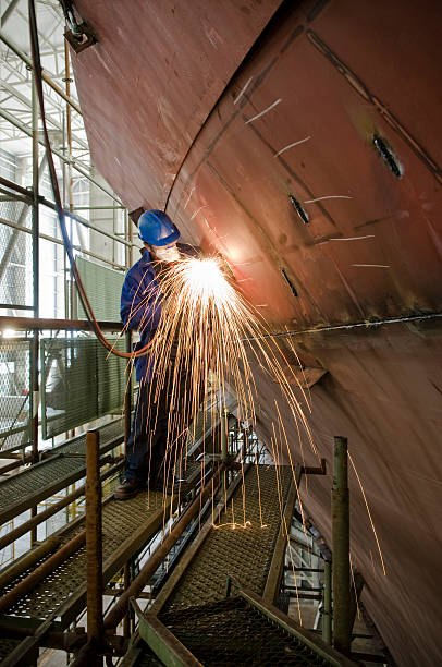 Metalworker Welding new steel plates on a ship's hull during repair work on a ship in a dry dock. dry dock stock pictures, royalty-free photos & images