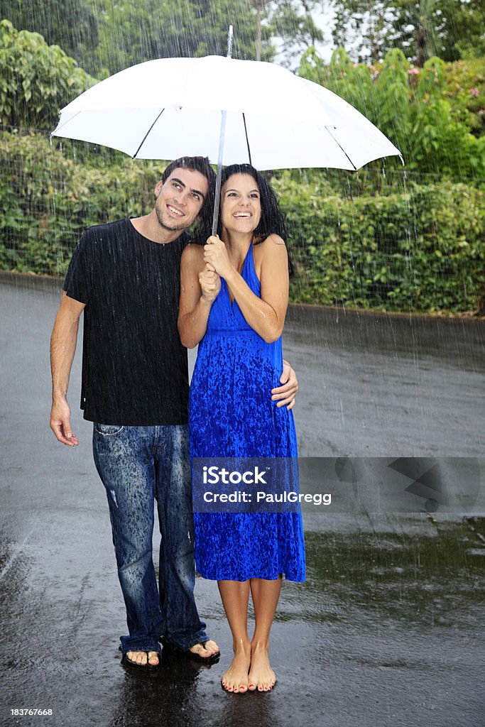 Jovem casal com guarda-sol em pé na chuva. - Foto de stock de Adolescente royalty-free