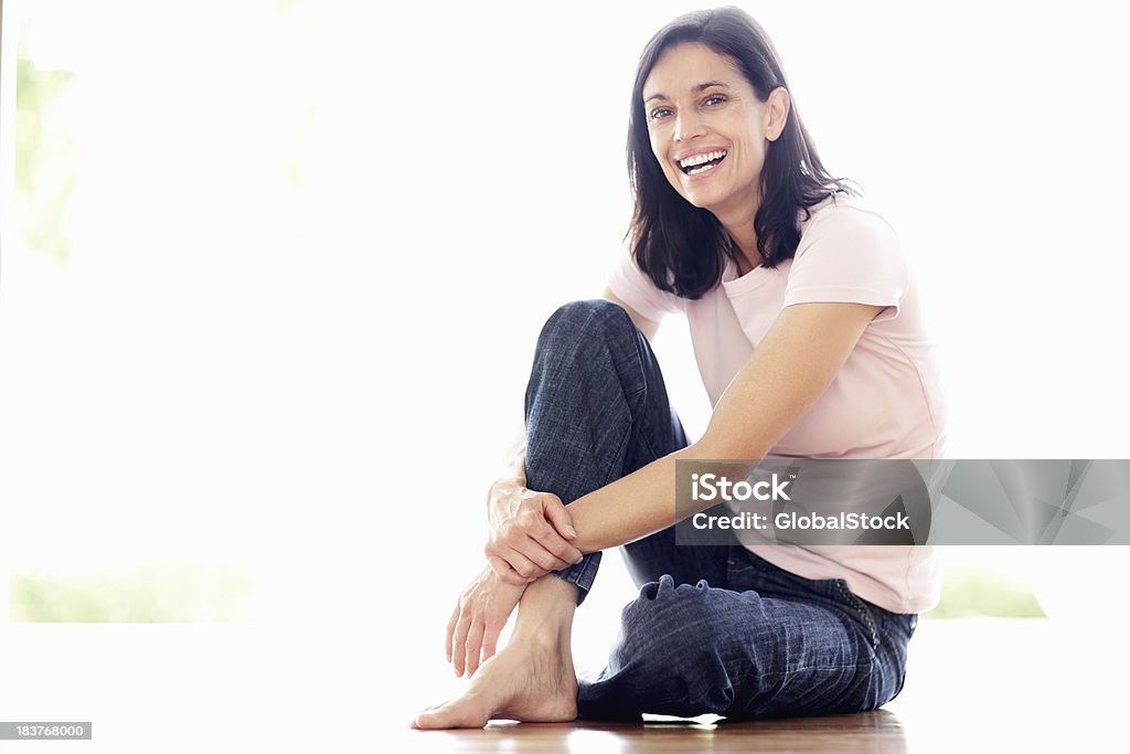 Mature woman laughing Full length of cheerful mature woman sitting on floor - copyspace Laughing Stock Photo