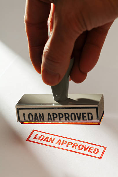 istock Hand Holding Rubber Stamp Stamping Red “LOAN APPROVED” on White 183768215