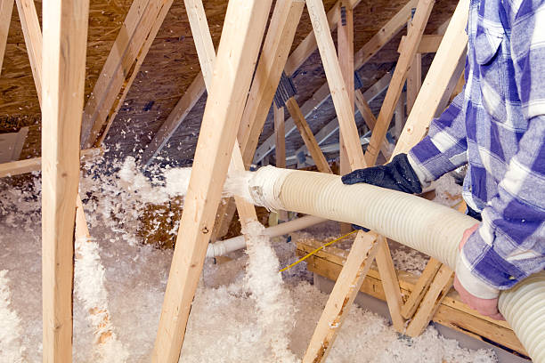 istock Worker Spraying Blown Fiberglass Insulation between Attic Trusses 183768427