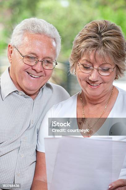 Madura Pareja Hablando Y Sonriente Mirando A Documento Foto de stock y más banco de imágenes de Adulto