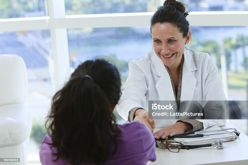 Donna pediatra medico stringe la mano di un adolescente - Foto stock royalty-free di 45-49 anni