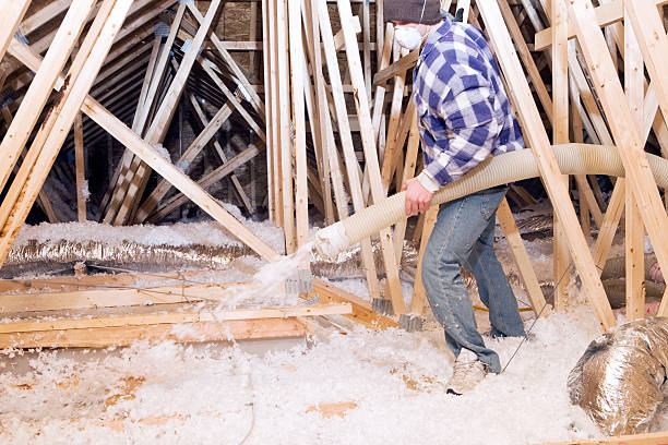 istock Worker Spraying Blown Fiberglass Insulation between Attic Trusses 183768691