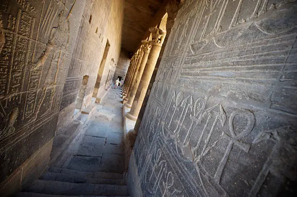"Walls of ancient colonnade in Philae, Aswan are lined with Egyptian hieroglyphics and columns"