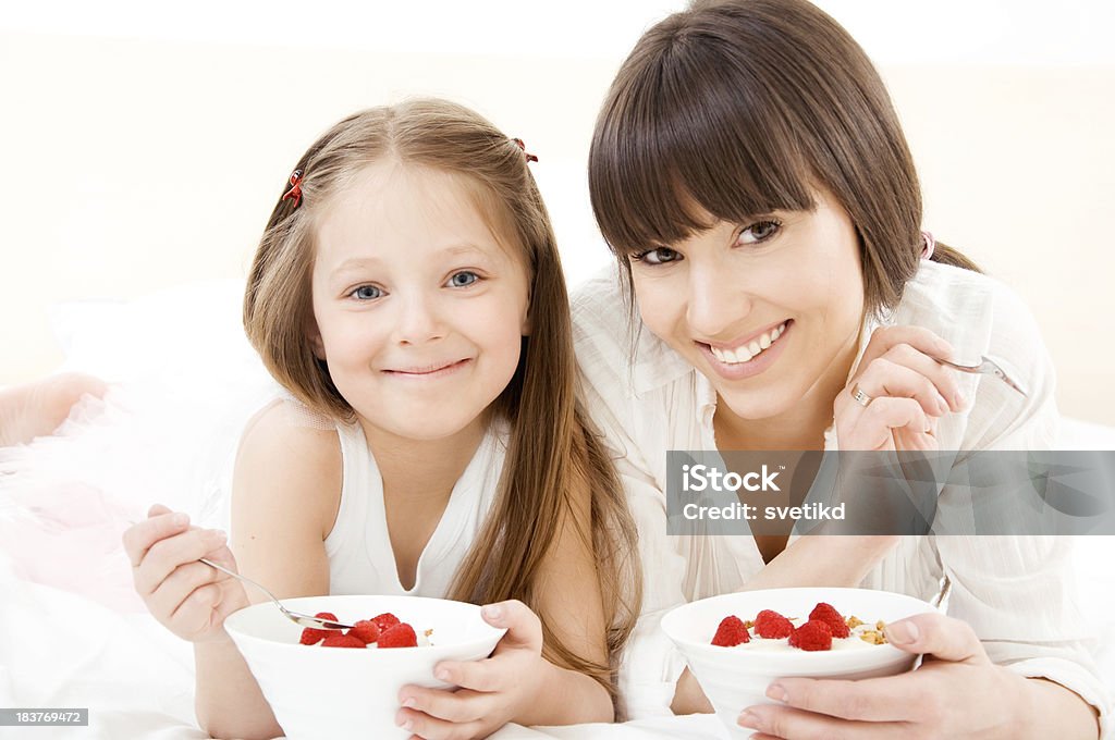 Healthy eating Happy smiling mother and daughter lying on bed and eating healthy food together. Looking at camera. 25-29 Years Stock Photo