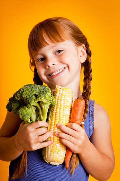 istock Happy, Smiling Young Girl Holding Broccoli, Corn, Carrot 183769716