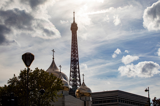 Paris skyline - Eiffel tower and the architectural domes on an Orthodox church against a dramatic sky