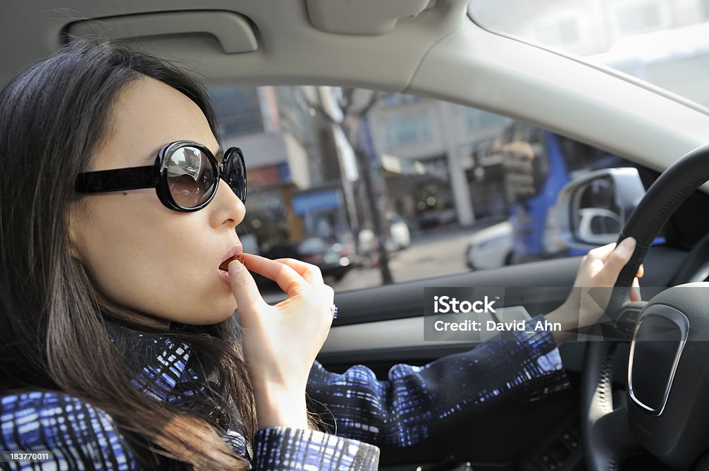 Giovane donna avendo uno spuntino durante la guida - Foto stock royalty-free di Mangiare