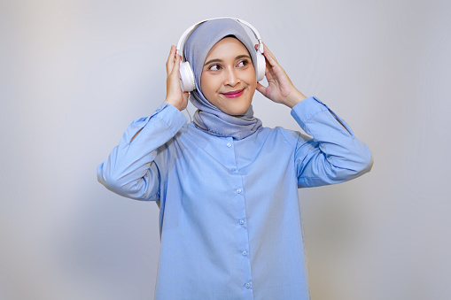 happy young Asian muslim woman listening music with headphone. muslim woman advertising concept. listening music concept