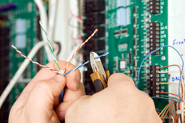 Electrician Cutting Small Paired Wire with Blurred PC Board Background  pliers stock pictures, royalty-free photos & images