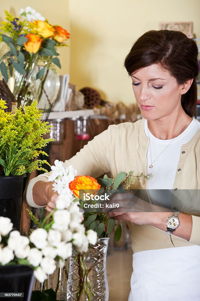 Mujer joven trabajando en tienda de floristería flores de precisión - Foto de stock de 20 a 29 años libre de derechos