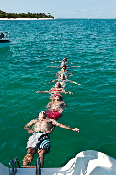 A group of holiday makers on vacation form a human chain from the back of a luxury yacht anchored off Bazaruto Island in the Mozambique archipelago.