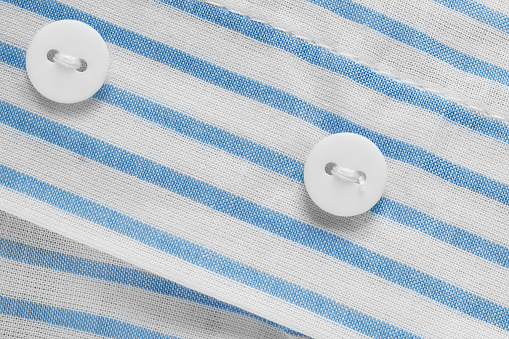 White small clothes buttons on white and blue cotton fabric