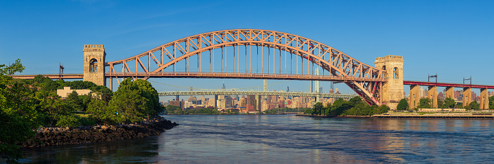 High resolution stitched panorama of The Hell Gate Bridge with Water of East River and Robert F Kennedy (RFK) Triborough Bridge and Skyscrapers of Manhattan Upper East Side in Background on a Clear Morning, Queens, New York, USA. The Hell Gate Bridge is a Railroad Bridge between Astoria in Queens and Randalls and Wards Islands in Manhattan.  Canon EOS 6D (Full Frame censor) DSLR. Canon EF 85mm f/1.8 USM Prime Lens. 3:1 Image Aspect Ratio. This image was downsized to 50MP. Original image resolution is 62MP or 13682 x 4561 px.
