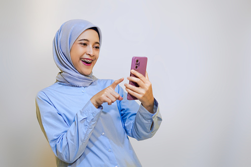 Young muslim woman cheerfully online shopping on her phone. online shopping concept with mobile phone