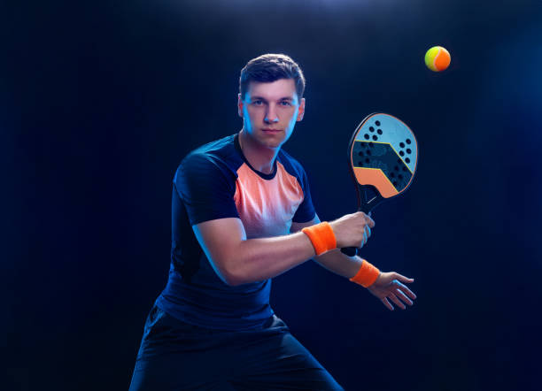 Beach tennis player with racket. Man athlete playing isolated on black background. stock photo