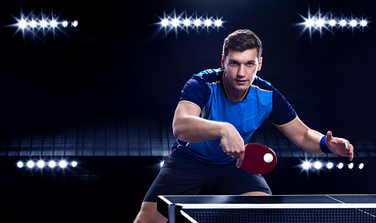 Close up of unrecognizable man having fun while playing table tennis outdoors.