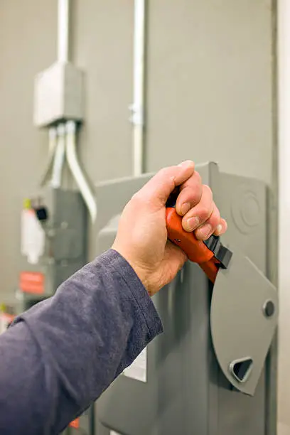 Photo of Worker Throwing Lever Switch on a Main Electrical Power Enclosure