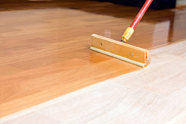 istock Squeegee Style Brush Applying Clear Polyurethane to Hardwood Floor 183771871