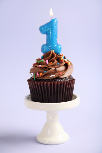 XXXL.  Chocolate cupcake with sprinkles and a first birthday candle on top.