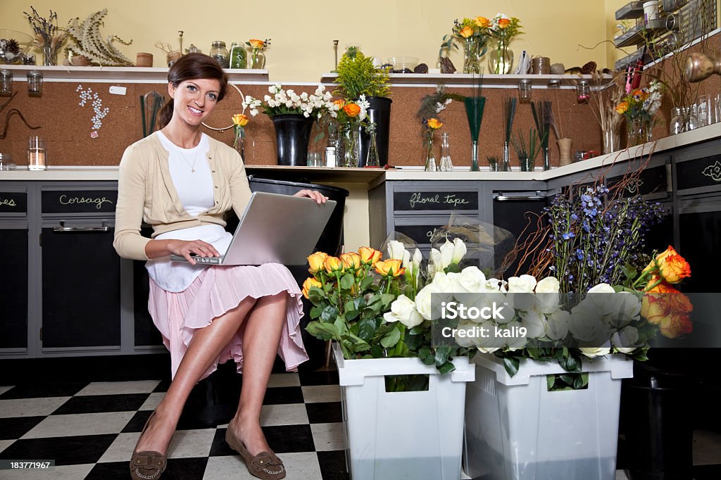 Jeune femme travaillant dans fleuriste boutique avec ordinateur portable - Photo de Bonheur libre de droits