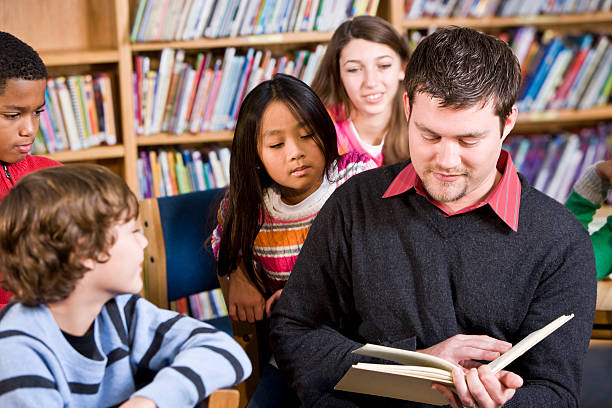 istock Teacher or librarian reading to group of children 183773132