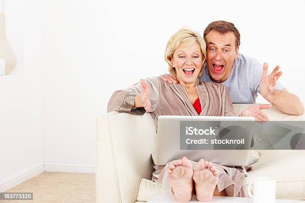 Pareja Madura Feliz Usando Una Computadora Portátil En La Sala De Estar Foto de stock y más banco de imágenes de 50-59 años